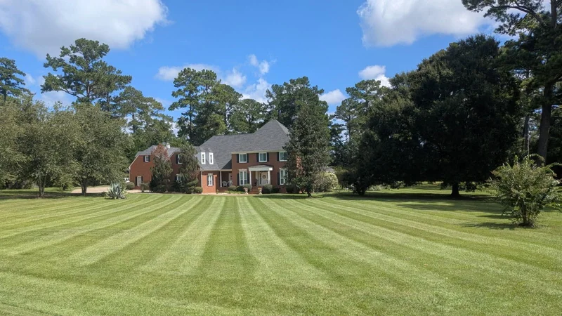A spacious striped lawn in front of a brick home